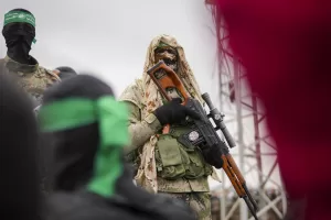 A Hamas fighter in combat fatigues stands before the ceremony for the handover of Israeli hostages to the Red Cross in Nuseirat, central Gaza Strip, Saturday, Feb. 22, 2025. (AP Photo/Abdel Kareem Hana)