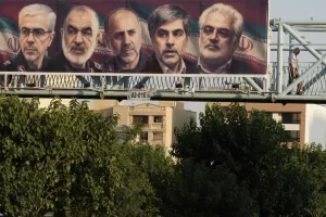 A man walks past a billboard displaying images of top Iranian commanders and scientists killed in Israeli strikes early Friday, in Tehran, Iran, Friday, June 13, 2025. (AP Photo/Vahid Salemi)